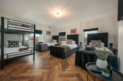 a bedroom with three beds and a table with a vase at The Boot Rooms Anfield in Liverpool
