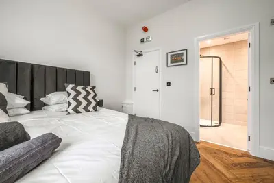 a bedroom with a white bed with a black headboard at The Boot Rooms Anfield in Liverpool