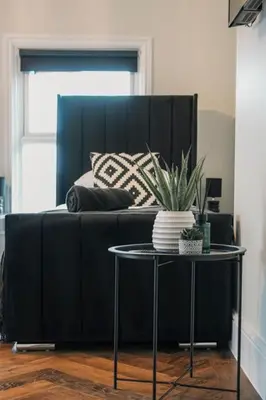 a bed with a black headboard and a table with a plant at The Boot Rooms Anfield in Liverpool