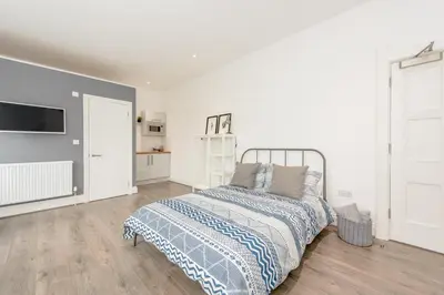 a white bedroom with a bed and a tv at No 27 Liverpool in Liverpool