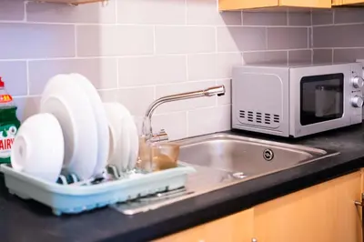 a sink with dishes in a dish rack next to a microwave at Westminster Apartment in Liverpool