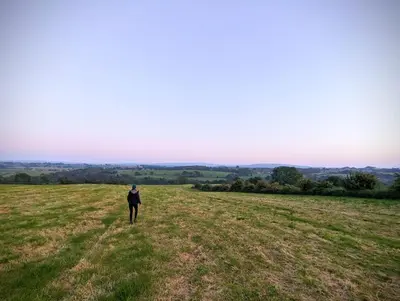 a man walking in a field of grass at Luxury 18th Century Stone Built Cottage in Lower Bentham
