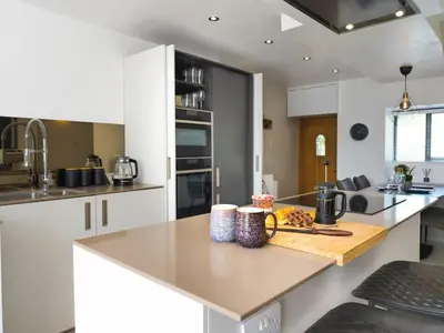 a kitchen with white cabinets and a counter top at Luxury 18th Century Stone Built Cottage in Lower Bentham