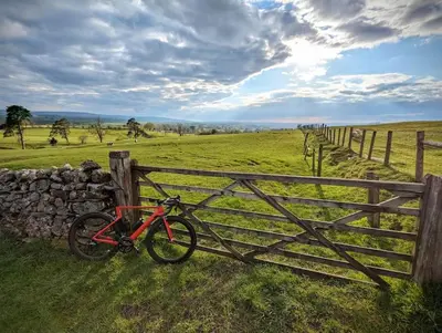a red bike parked next to a wooden fence at Luxury 18th Century Stone Built Cottage in Lower Bentham