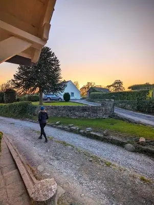a person walking down a gravel road with a tree at Luxury 18th Century Stone Built Cottage in Lower Bentham