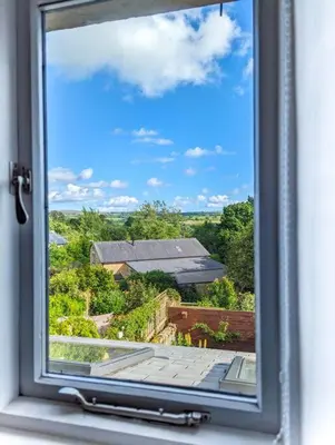 an open window with a view of a house at Luxury 18th Century Stone Built Cottage in Lower Bentham