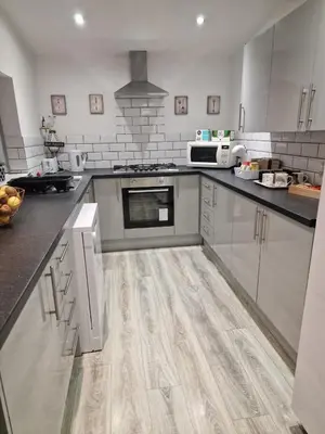 a kitchen with white cabinets and a wooden floor at Luxury house in Kensington for 21 guests in Liverpool
