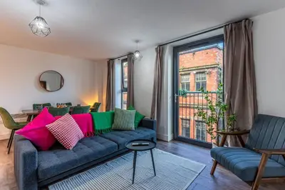 a living room with a blue couch with colorful pillows at Top Floor City Stay Beatles Bars & Nightlife in Liverpool