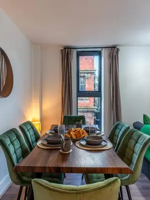 a dining room with a wooden table and green chairs at Top Floor City Stay Beatles Bars & Nightlife in Liverpool