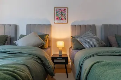 two beds in a room with a lamp on a table at Top Floor City Stay Beatles Bars & Nightlife in Liverpool