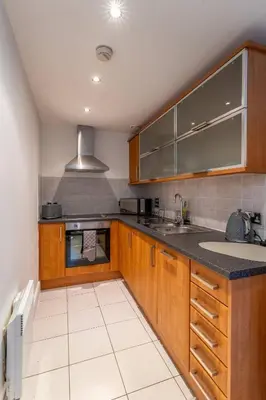 a kitchen with wooden cabinets and a sink at Top Floor City Stay Beatles Bars & Nightlife in Liverpool