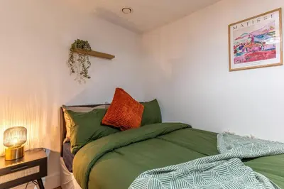 a bedroom with a bed with green sheets at Top Floor City Stay Beatles Bars & Nightlife in Liverpool