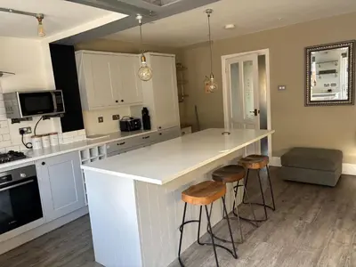 a kitchen with a white counter and stools at Williamson House Lancaster in Lancaster