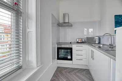 a white kitchen with a sink and a stove at Glendale House by Guestz in Lytham St Annes