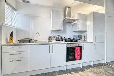 a white kitchen with white cabinets and appliances at Glendale House by Guestz in Lytham St Annes