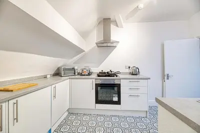 a kitchen with white cabinets and a stove top oven at Glendale House by Guestz in Lytham St Annes