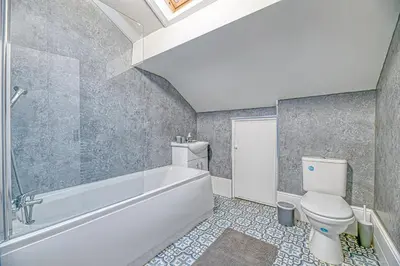 a bathroom with a white tub and a toilet at Glendale House by Guestz in Lytham St Annes