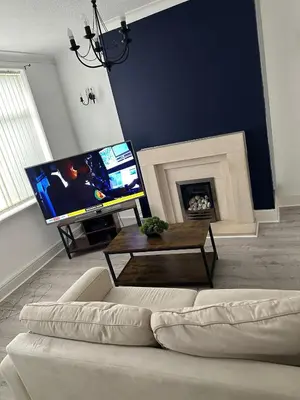 a living room with a white couch and a fireplace at Abigail house in Westhoughton