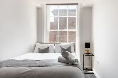 a white bedroom with a bed in front of a window at Liverpool City Haven 1-Bed Apartment for Couples & Solo Travelers in Liverpool