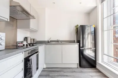a kitchen with white cabinets and a stainless steel refrigerator at Liverpool City Haven 1-Bed Apartment for Couples & Solo Travelers in Liverpool