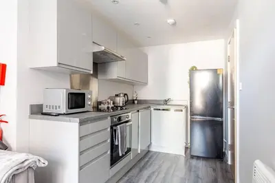 a kitchen with white cabinets and a stainless steel refrigerator at Modern 1-Bedroom City Centre Apartment, Liverpool Hideaway in Liverpool