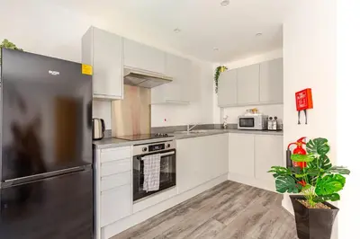 a kitchen with white cabinets and a stainless steel refrigerator at Bright 1-Bed Apartment In City Centre Liverpool in Liverpool