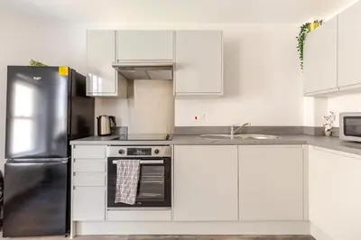 a kitchen with white cabinets and a stainless steel refrigerator at Bright 1-Bed Apartment In City Centre Liverpool in Liverpool