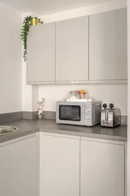 a kitchen with white cabinets and a microwave at Bright 1-Bed Apartment In City Centre Liverpool in Liverpool
