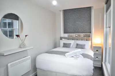 a white bedroom with a white bed and a mirror at City Comfort Modern 1-Bed Apartment sleeps up to 4 in Liverpool