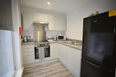 a kitchen with white cabinets and a black refrigerator at City Comfort Modern 1-Bed Apartment sleeps up to 4 in Liverpool