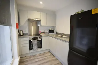a kitchen with white cabinets and a black refrigerator at City Comfort Modern 1-Bed Apartment sleeps up to 4 in Liverpool