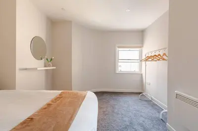 a white bedroom with a bed and a mirror at 1-BD Apartment with Sofa Bed In The Heart of Liverpool in Liverpool