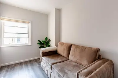 a leather couch in a living room with a window at 1-BD Apartment with Sofa Bed In The Heart of Liverpool in Liverpool