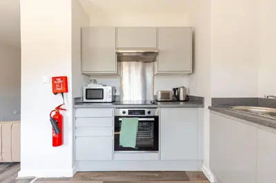 a kitchen with white cabinets and a stove top oven at Liverpool City Stay 1-Bed apartment with 2 Sofa Beds, Sleeps up to 6 in Liverpool