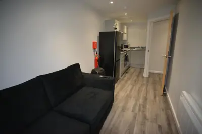 a living room with a black couch and a kitchen at Walk to City Hotspots Liverpool 1BD Apartment in Liverpool