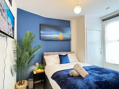 a bedroom with a bed with a blue wall at TV in Every Room Free Parking in Liverpool