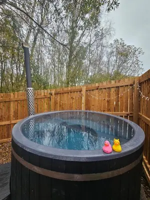 a barrel hot tub with two rubber shoes in it at The Laurels - Wood Fired Hot Tub and Firepit in Poulton le Fylde