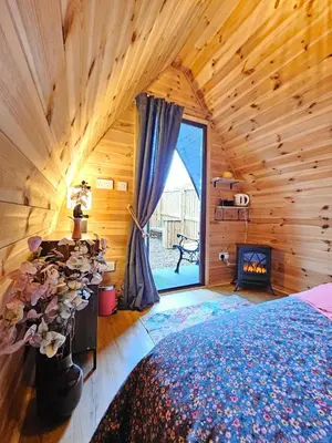a bedroom in a log cabin with a bed and a fireplace at The Laurels - Wood Fired Hot Tub and Firepit in Poulton le Fylde