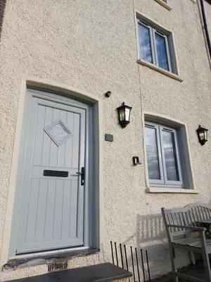 a white door on the side of a building with a bench at Sunny Bank, Cark-in-Cartmel in Cark