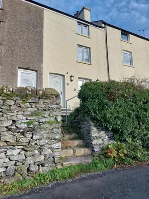 a stone wall and stairs in front of a building at Sunny Bank, Cark-in-Cartmel in Cark