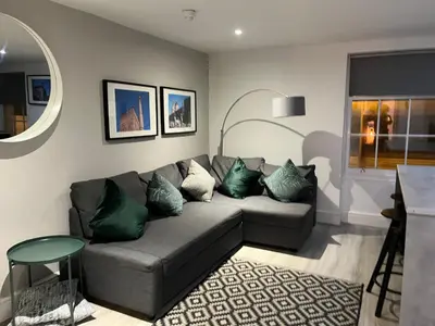 a living room with a gray couch with green pillows at Jude's Place One Bedroom Apartments in Liverpool