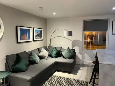 a living room with a gray couch with green pillows at Jude's Place One Bedroom Apartments in Liverpool