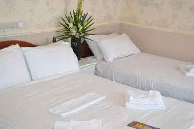 a room with two beds and a vase with flowers at Lyndene Hotel in Blackpool