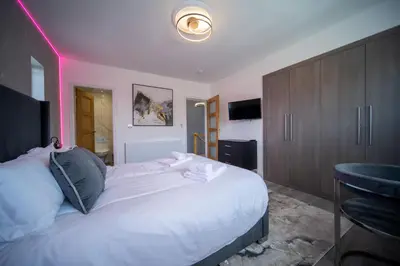 a bedroom with a large white bed with a purple light at 20 Guest Luxury Stay - Private Pool, Hot Tub & Gym in Lytham St Annes