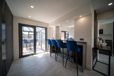 a kitchen with a bar with blue bar stools at 20 Guest Luxury Stay - Private Pool, Hot Tub & Gym in Lytham St Annes