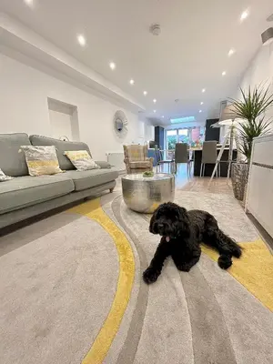 a black dog laying on a rug in a living room at Mode Cottage in Lytham St Annes
