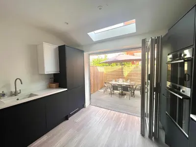 a kitchen with black cabinets and a table with an umbrella at Mode Cottage in Lytham St Annes