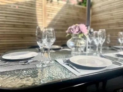a table with glasses and plates and a vase with flowers at Mode Cottage in Lytham St Annes