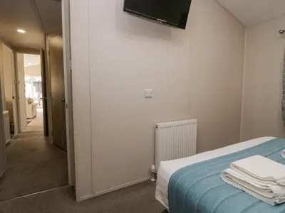 a room with a bed and a television on the wall at The Three Bears Lodge, Coniston Drive 11 in Carnforth