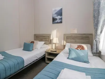 a room with two beds with a dog on the pillow at The Three Bears Lodge, Coniston Drive 11 in Carnforth